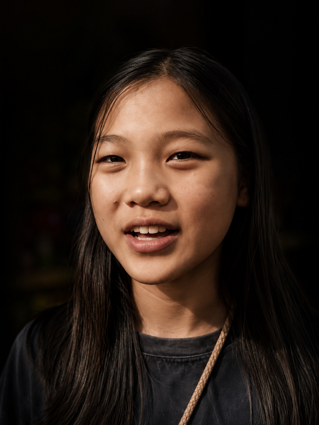 A young girl looking toward the camera, lit against a dark background